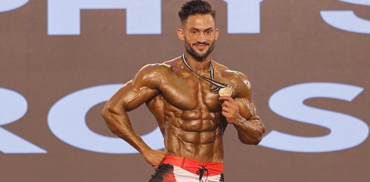Syed Bilal winning gold medal at bodybuilding championship stage.